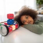 AI Robotics Cost - boy lying on bed playing with red and blue toy truck